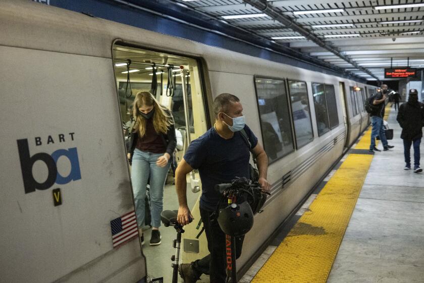 Passengers wearing masks depart a BART train in San Francisco, Calif.