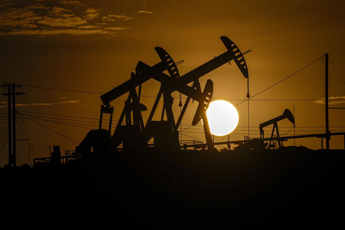 A setting sun silhouettes oil pumpjacks 