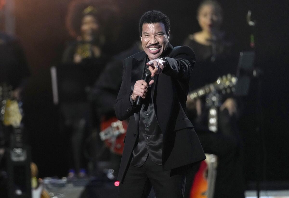 Lionel Richie points toward the audience during a performance.