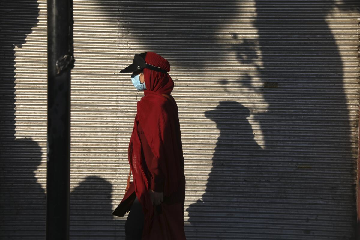 FILE - In this July 20, 2021 file photo, a woman wearing a protective face mask to help prevent the spread of the coronavirus walks on a sidewalk in southern Tehran, Iran. On Monday, Aug. 2, 2021, Iranian state media reported more than 37,000 new coronavirus infections, the country's single-day record so far in the pandemic. (AP Photo/Vahid Salemi)