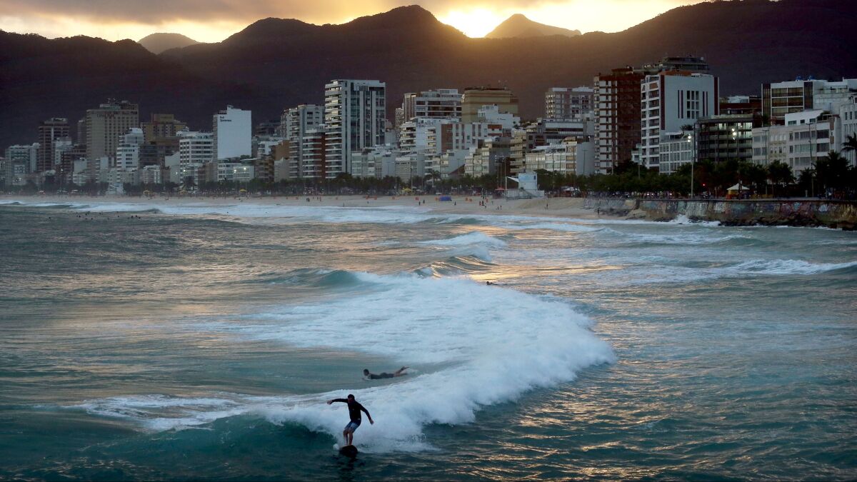 Surfers ride strong waves near Ipanema beach on May 25.