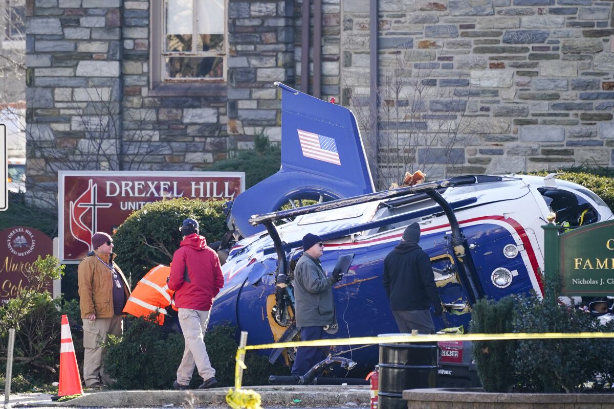 A medical helicopter rests next to the Drexel Hill United Methodist Church after it crashed in the Drexel Hill section of Upper Darby, Pa., on Wednesday, Jan. 12, 2022. Authorities and a witness say a pilot crash landed the medical helicopter without casualties in a residential area of suburban Philadelphia, miraculously avoiding a web of power lines and buildings as the aircraft fluttered, hit the street and slid into bushes outside a church.(AP Photo/Matt Rourke)