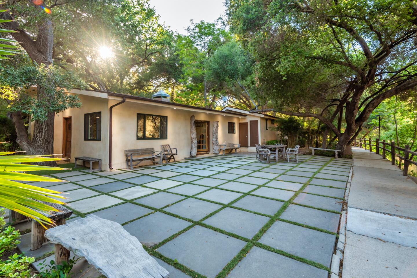 Square concrete tiles form a large patio behind a house.