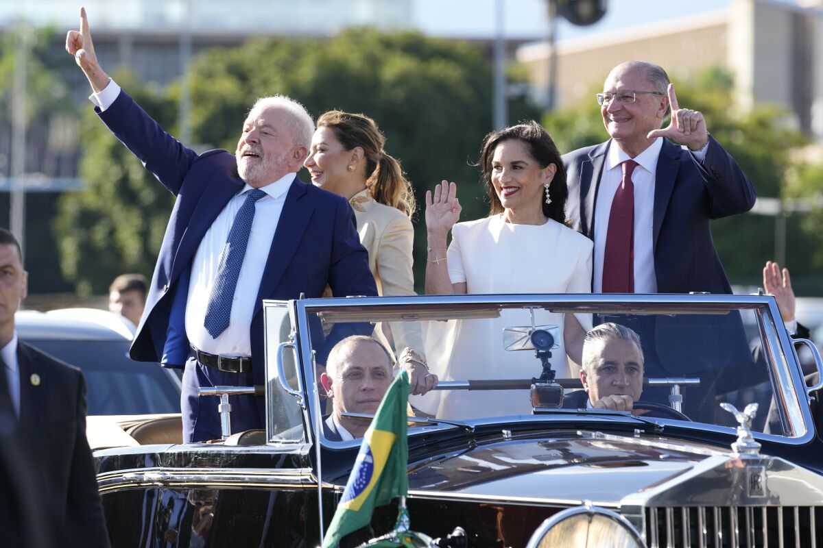 President Luiz Inacio Lula da Silva, left, his wife Rosangela da Silva, center left, wave to supporters on Jan. 1.