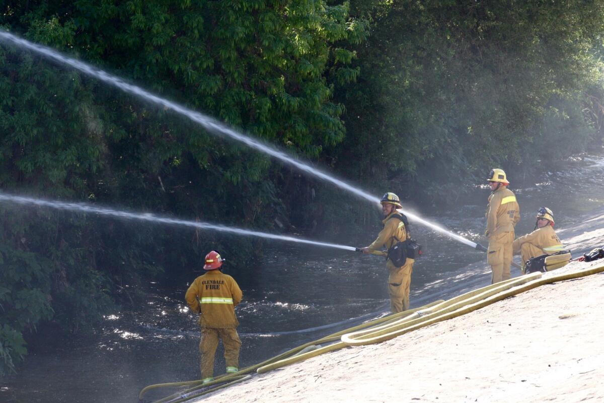 Firefighters hose the remains of a small fire in the LA River at Riverside Dr. on Monday, March 30, 2015.