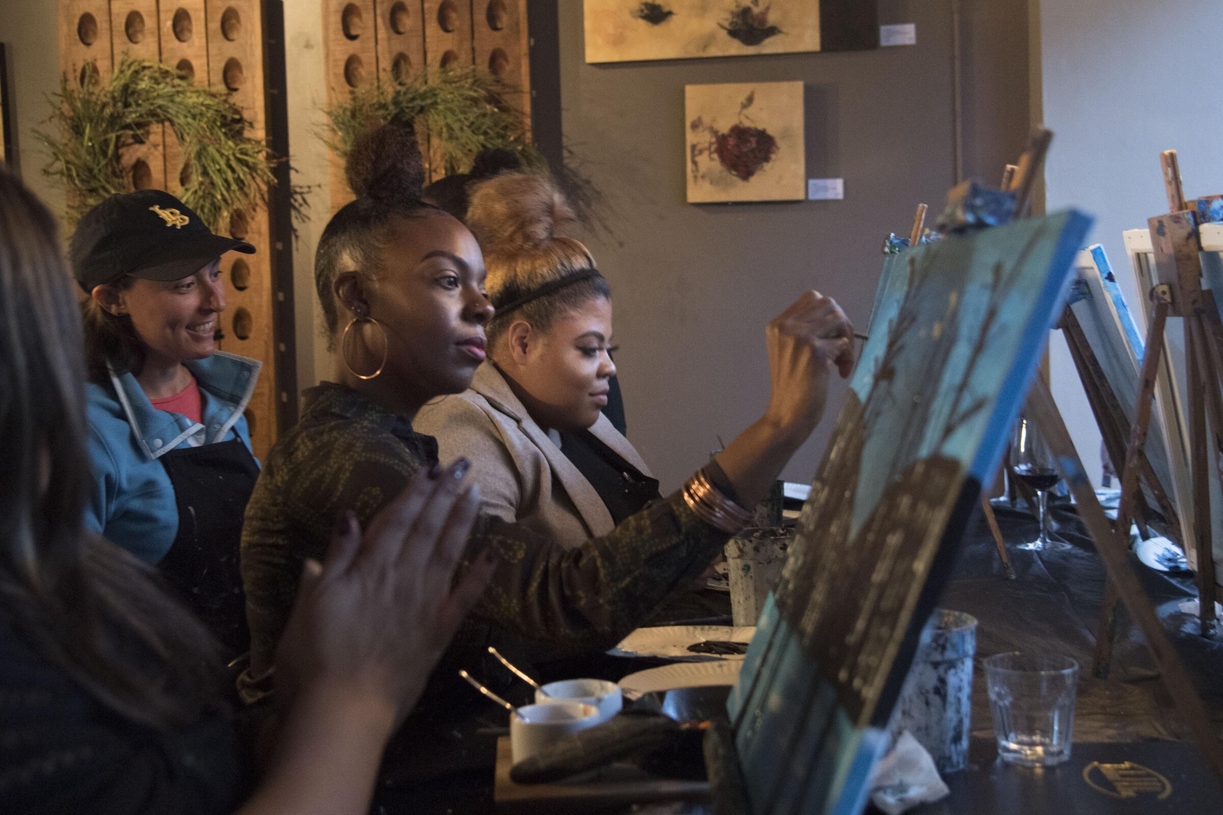Candice Branch of Corona, center, and Janelle Tarver, right, of Rancho Cucamonga, learn to paint at District Wine with Brushstrokes and Beverages, which partners with area businesses to hold painting classes in Long Beach's East Village.
