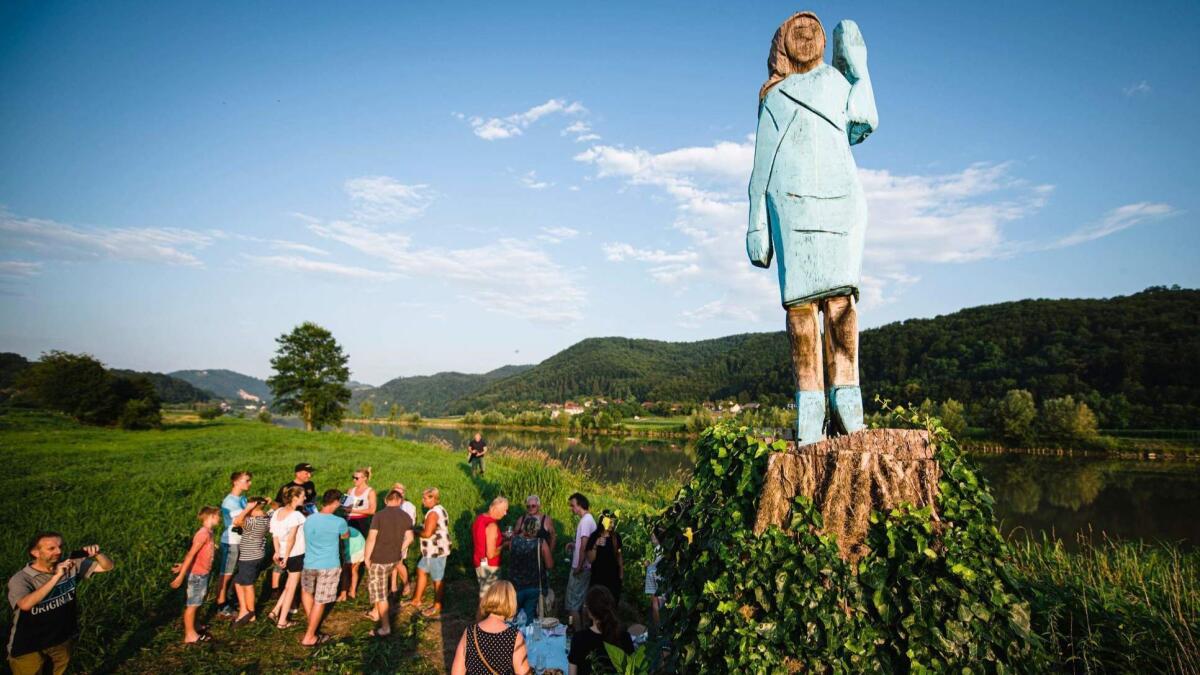 People gather around a sculpture of First Lady Melania Trump, set in the fields near her hometown of Sevnica, Slovenia.