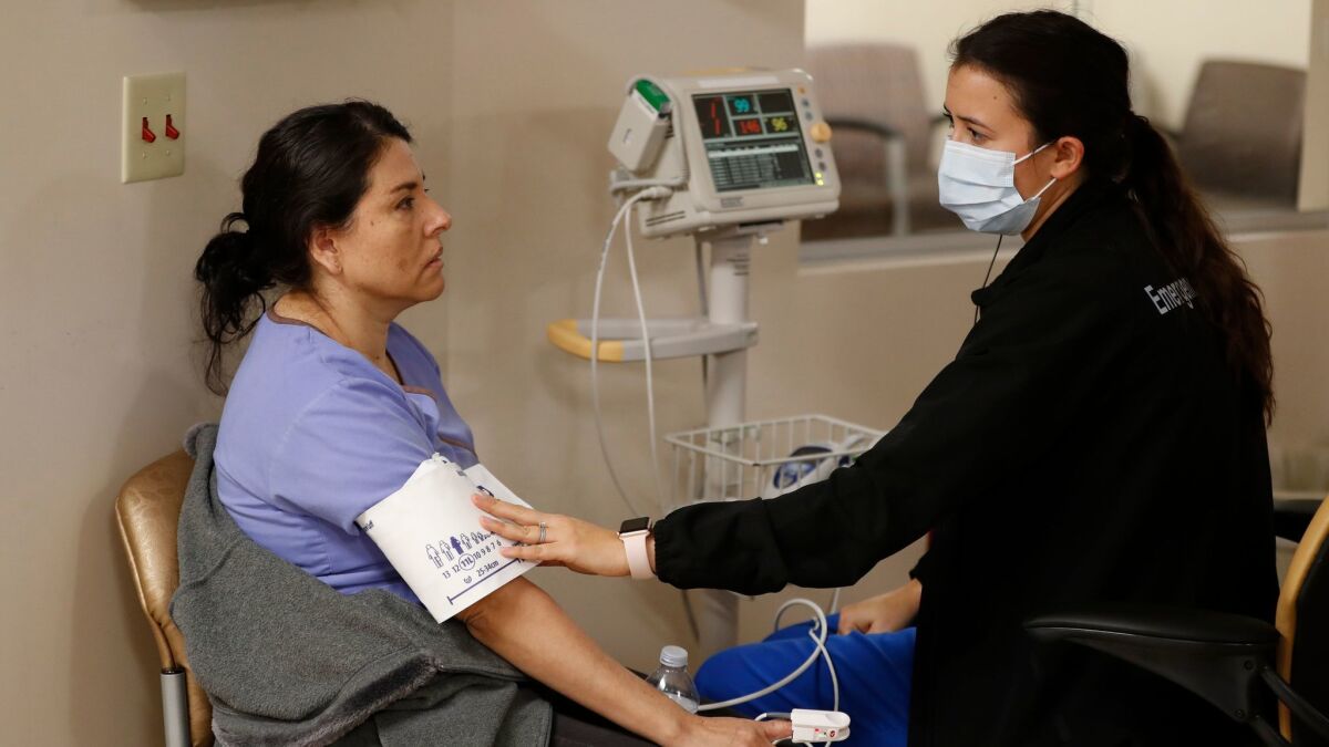 Marenna Bielman, right, takes Angelica Lara's blood pressure as she is treated for flu-like symptoms at St. Joseph Hospital in Orange.