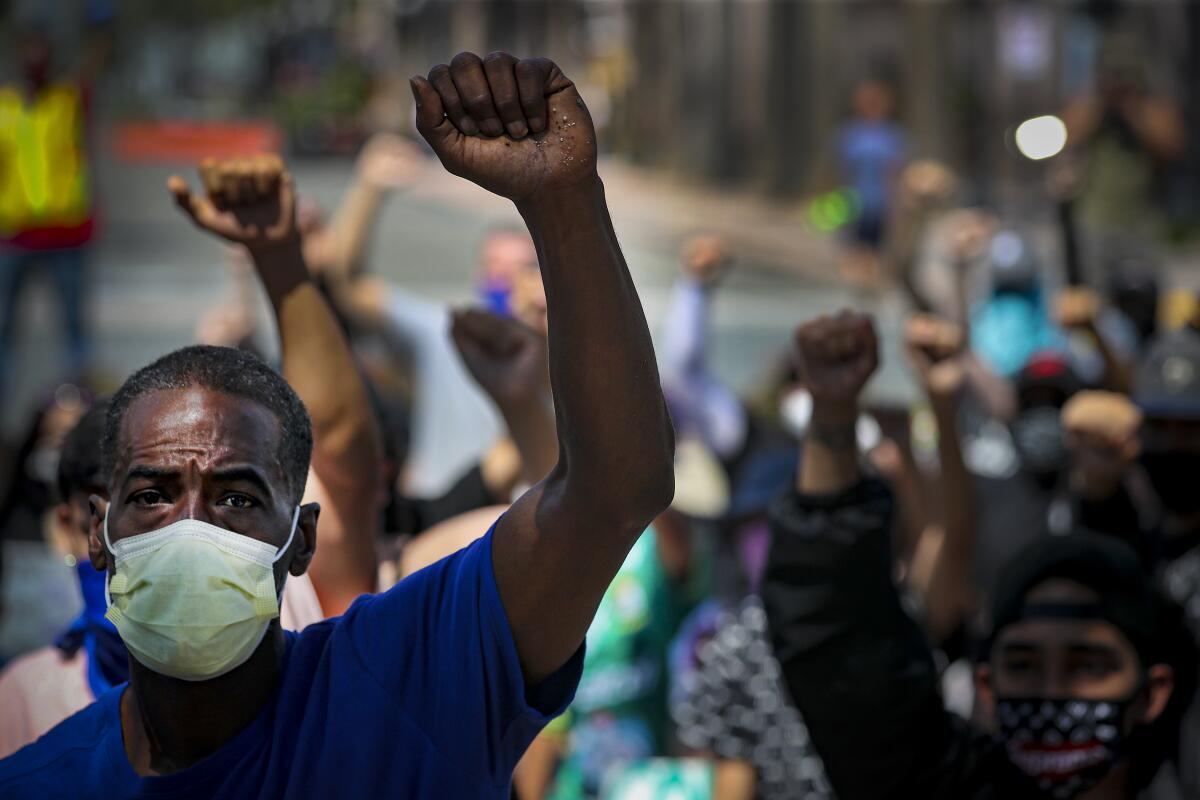 Protesters wearing face coverings and raising their fists rally at Anaheim City Hall on Wednesday.