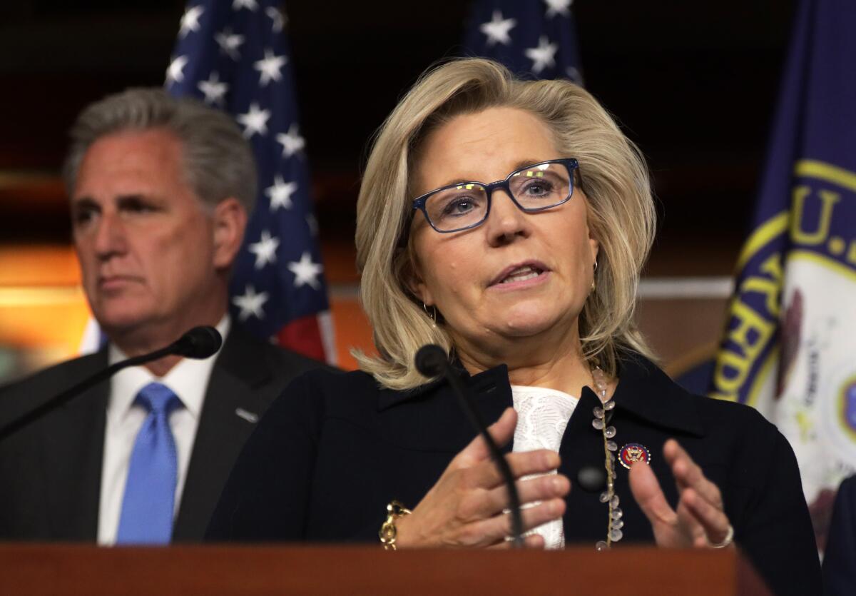Liz Cheney speaks at a lectern with Kevin McCarthy behind her.