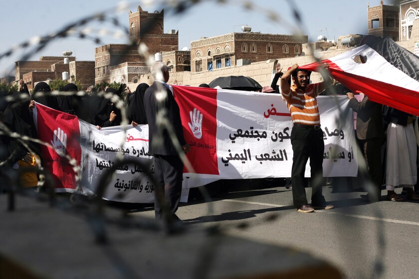 Yemenis carry a banner reading in Arabic, "We reject violence and terrorism in all forms" during a Saturday protest against the violence currently afflicting their country.