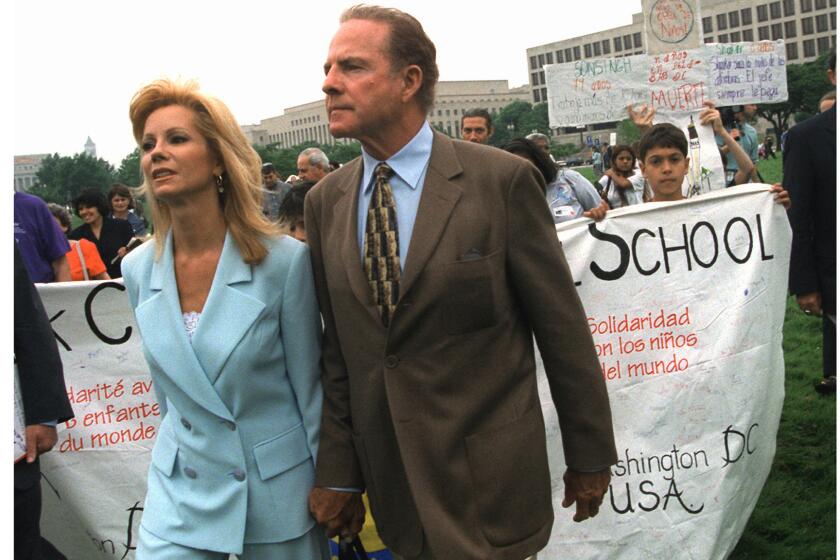 Hand in hand, Kathie Lee Gifford and her husband Frank Gifford leave a May 1998 rally in Washington, D.C., against child labor. Their activism was sparked by a scandal a year earlier involving her Wal-Mart clothing line.