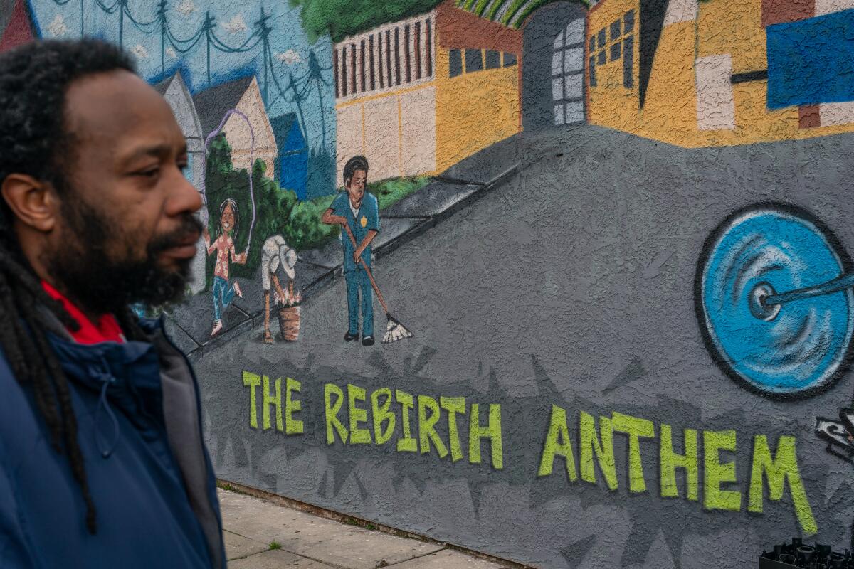 Artist Derrick Shavers looks at his mural, "The Rebirth Anthem."