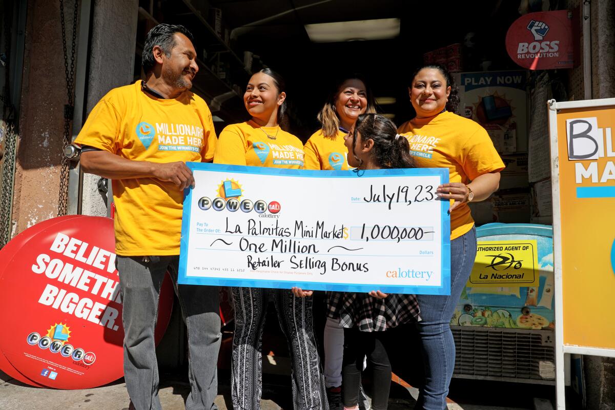 Maria Menjivar, center, poses with four other people and an oversized check 
