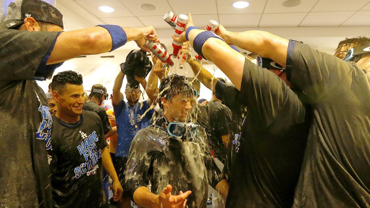 Dodgers douse a teammate during their celebration in the locker room after defeating the Rockies on Sunday to clinch the NL West title.