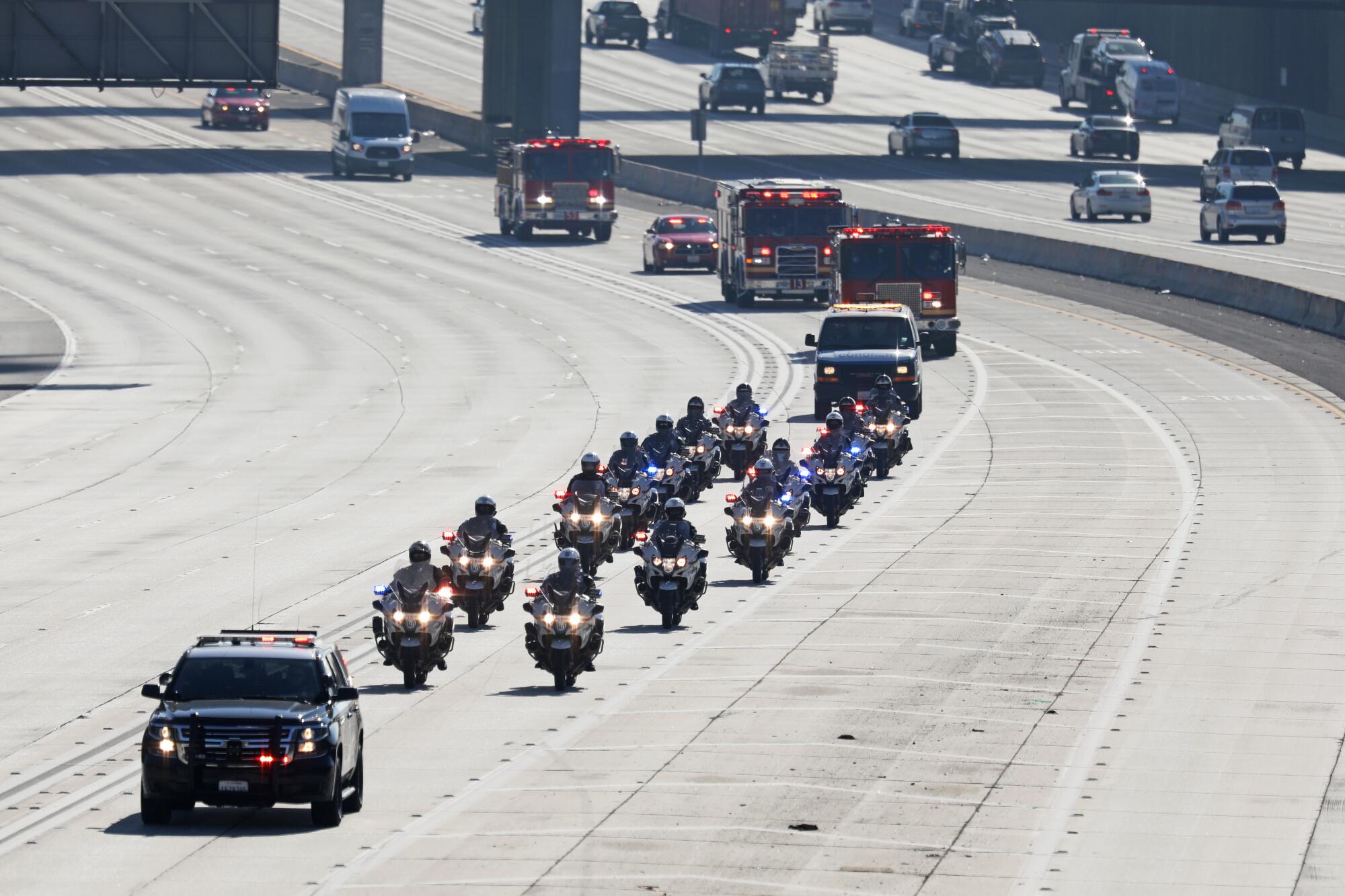A procession of police and fire vehicles on a freeway 