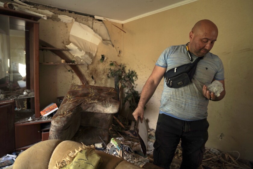A man searches through his destroyed apartment in Ukraine.