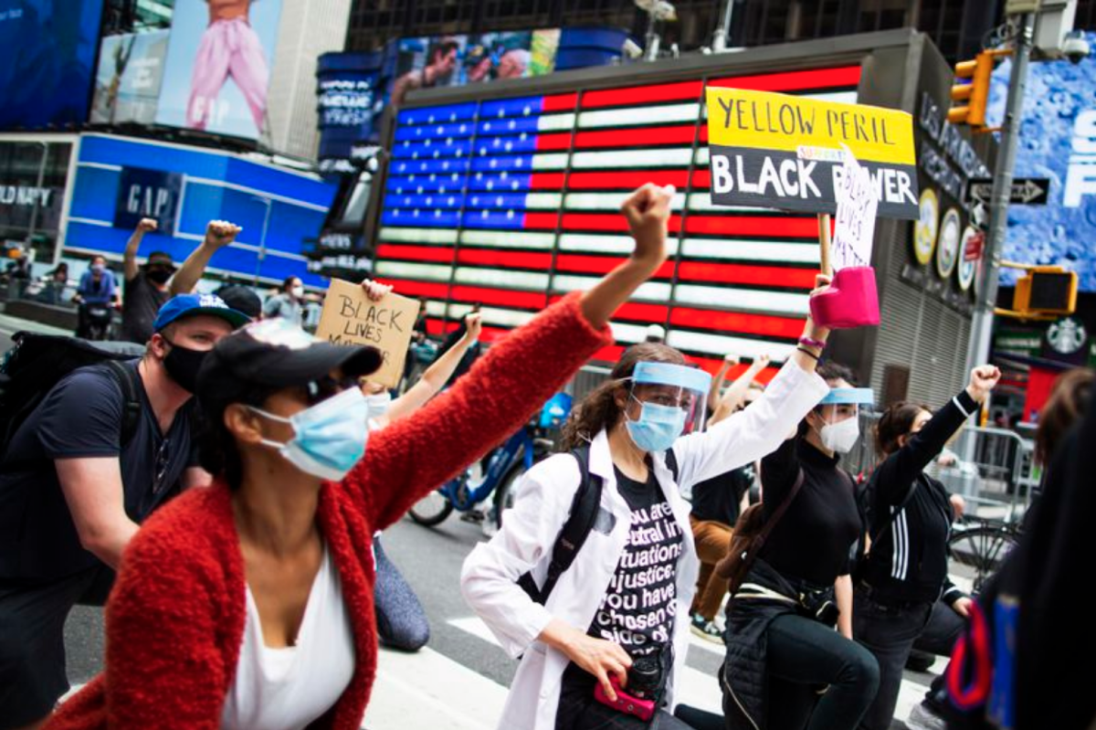 Manifestantes se arrodillan en señal de unidad durante una marcha solidaria por George Floyd.