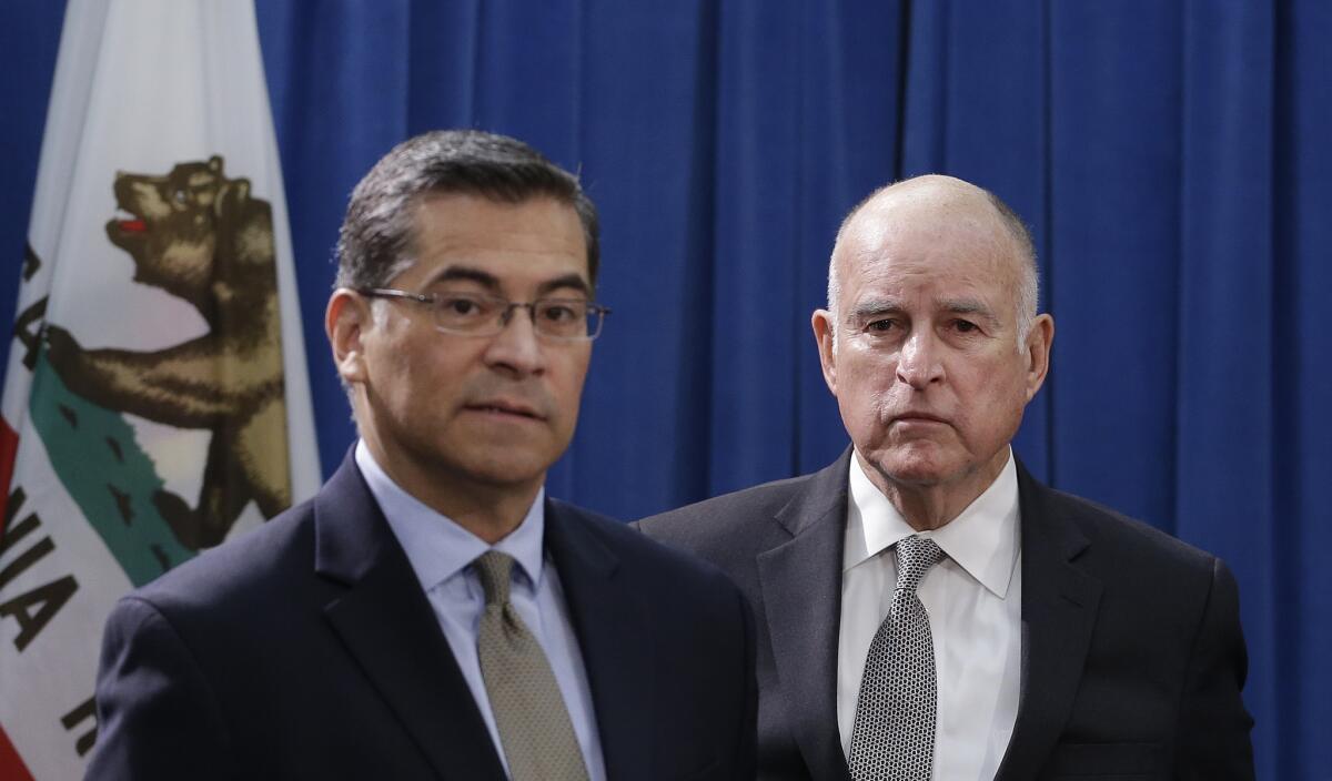 California Attorney General Xavier Becerra, left, and then-Gov. Jerry Brown appear at a Sacramento news conference in 2018. Just as Brown and Sen. Kamala Harris did when they were state attorney general, Becerra is writing slanted ballot descriptions for pending measures.