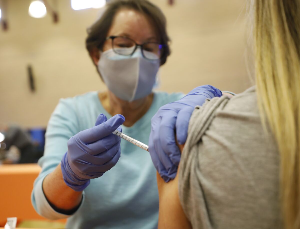 RN Debbie Ispen gives Sage Creek High teacher Lacey Hungerford the Pfizer COVID-19 vaccine at Cal State San Marcos