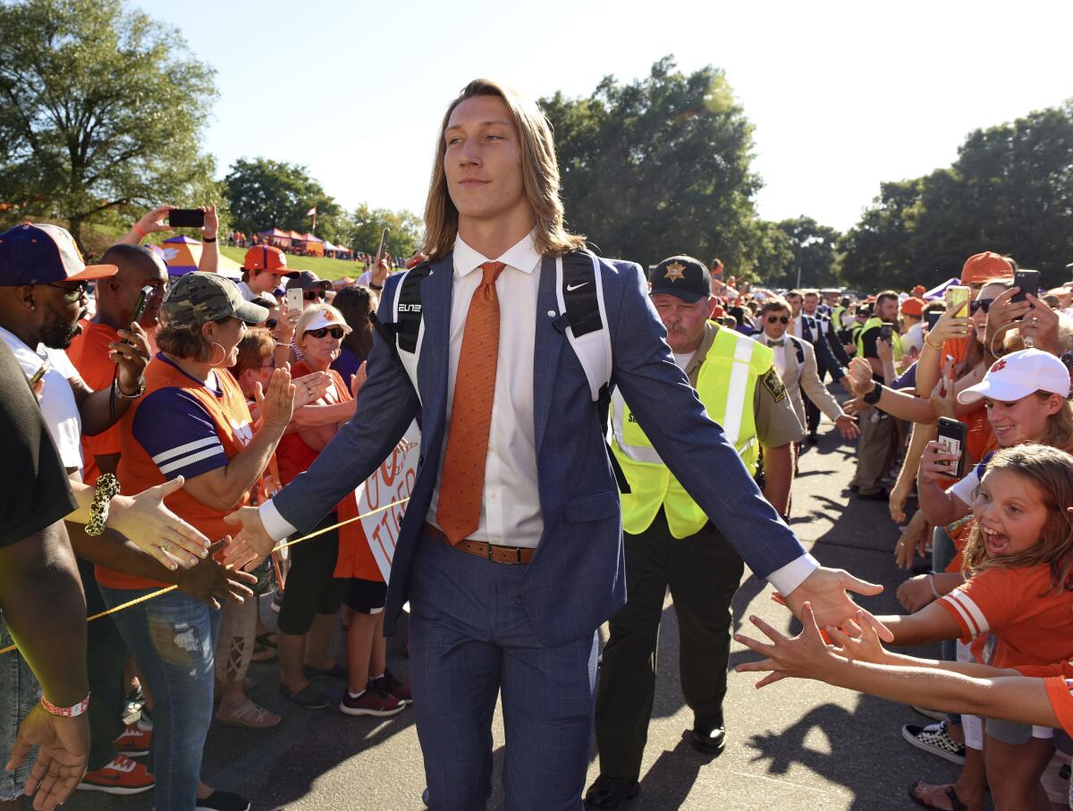 Clemson's Trevor Lawrence greets fans as he arrives for the team's NCAA college football game against Georgia Tech