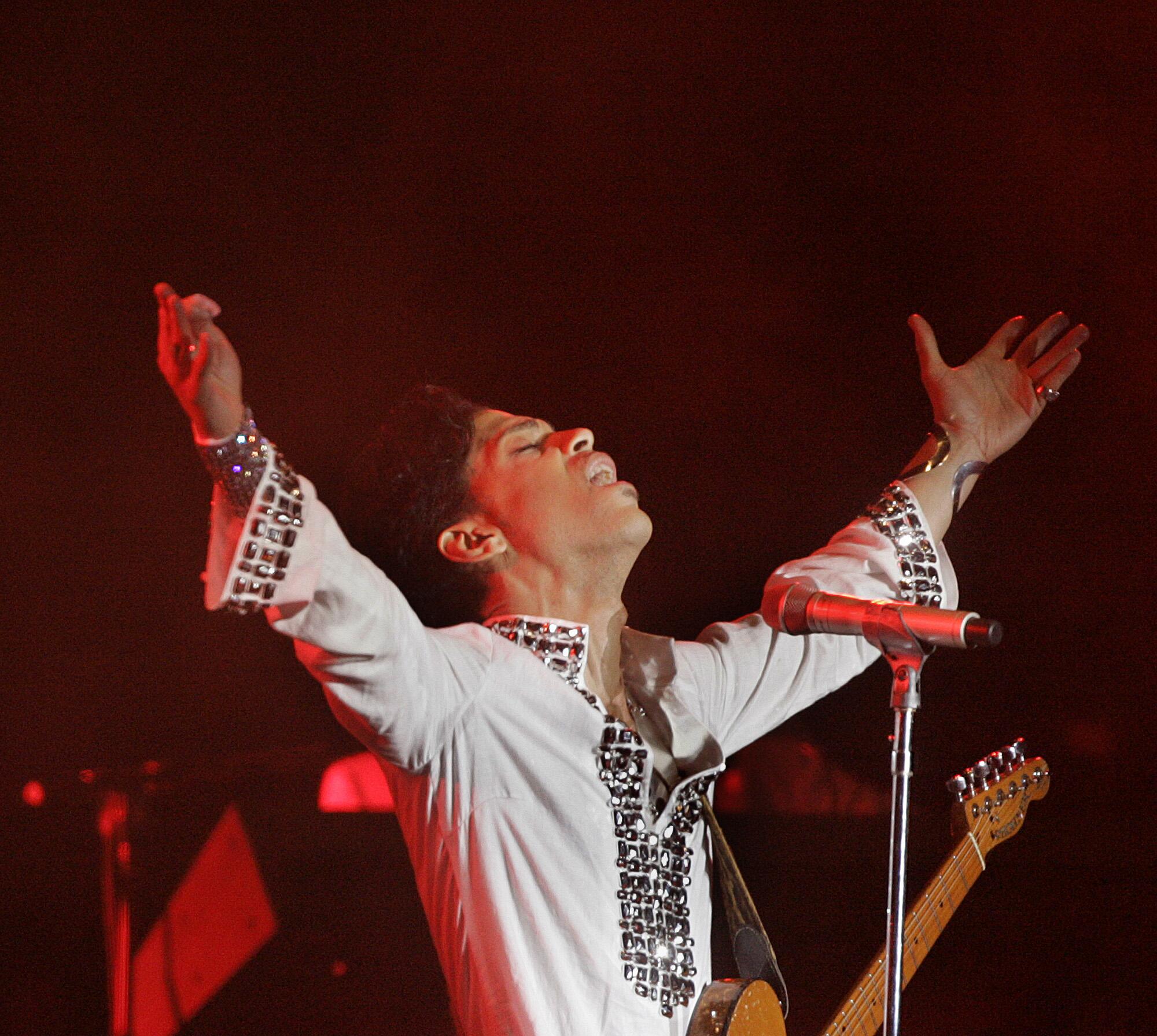 Prince stands down  a microphone with his arms outstretched and successful  the air