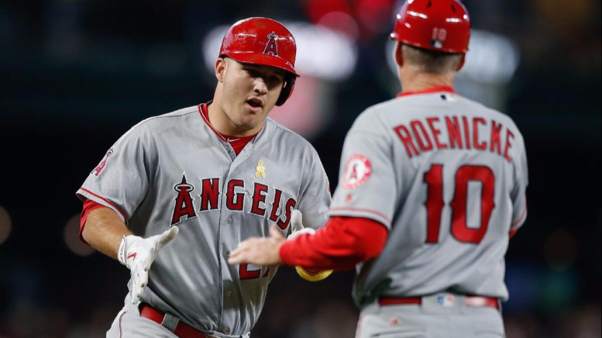 Mike Trout is congratulated by third base coach Ron Roenicke after hitting a three-run homer against the Mariners in the first inning of a game on Sept. 2.