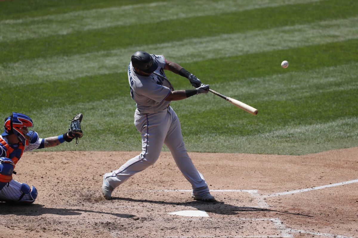 Miami Marlins' Jesus Aguilar, right, hits a fifth-inning solo home run during a baseball game against the New York Mets at Citi Field, Sunday, Aug. 9, 2020, in New York. (AP Photo/Kathy Willens)