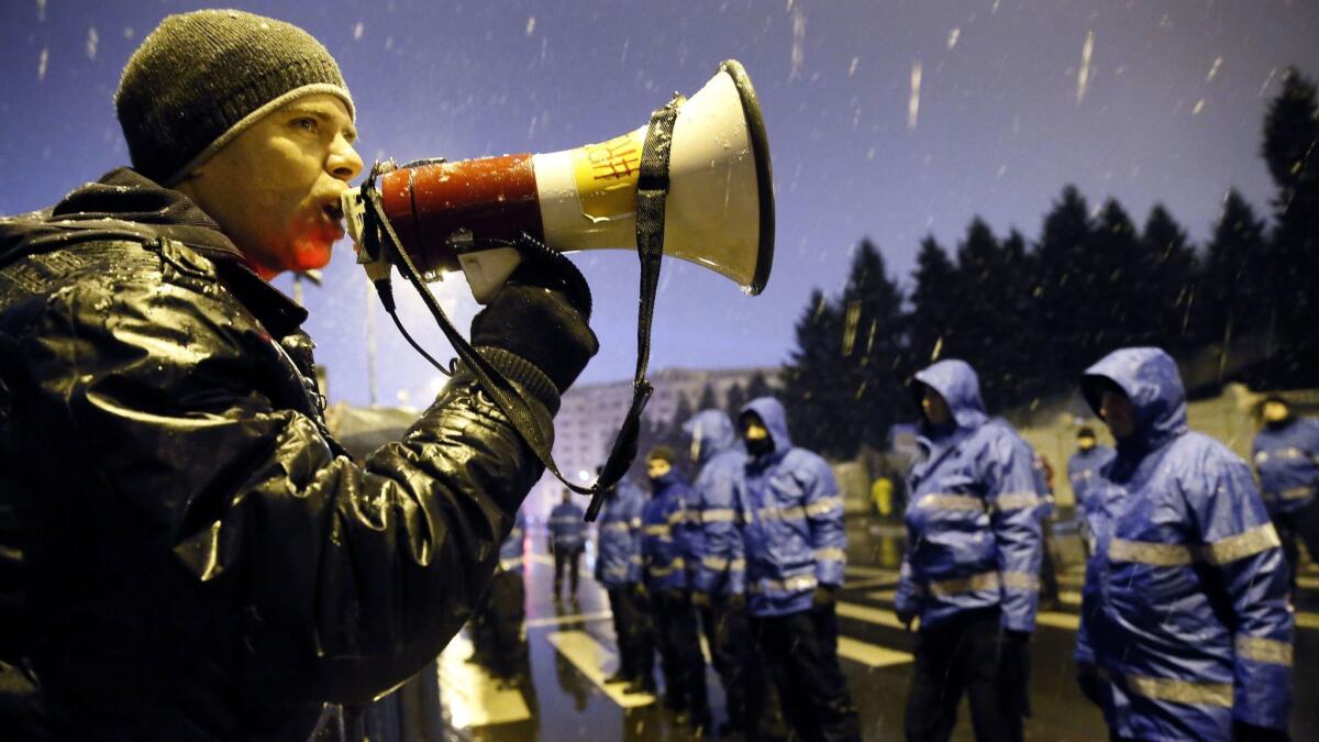 A Romanian demonstrator shouts slogans at riot police Dec. 17 in front of Parliament in Bucharest.