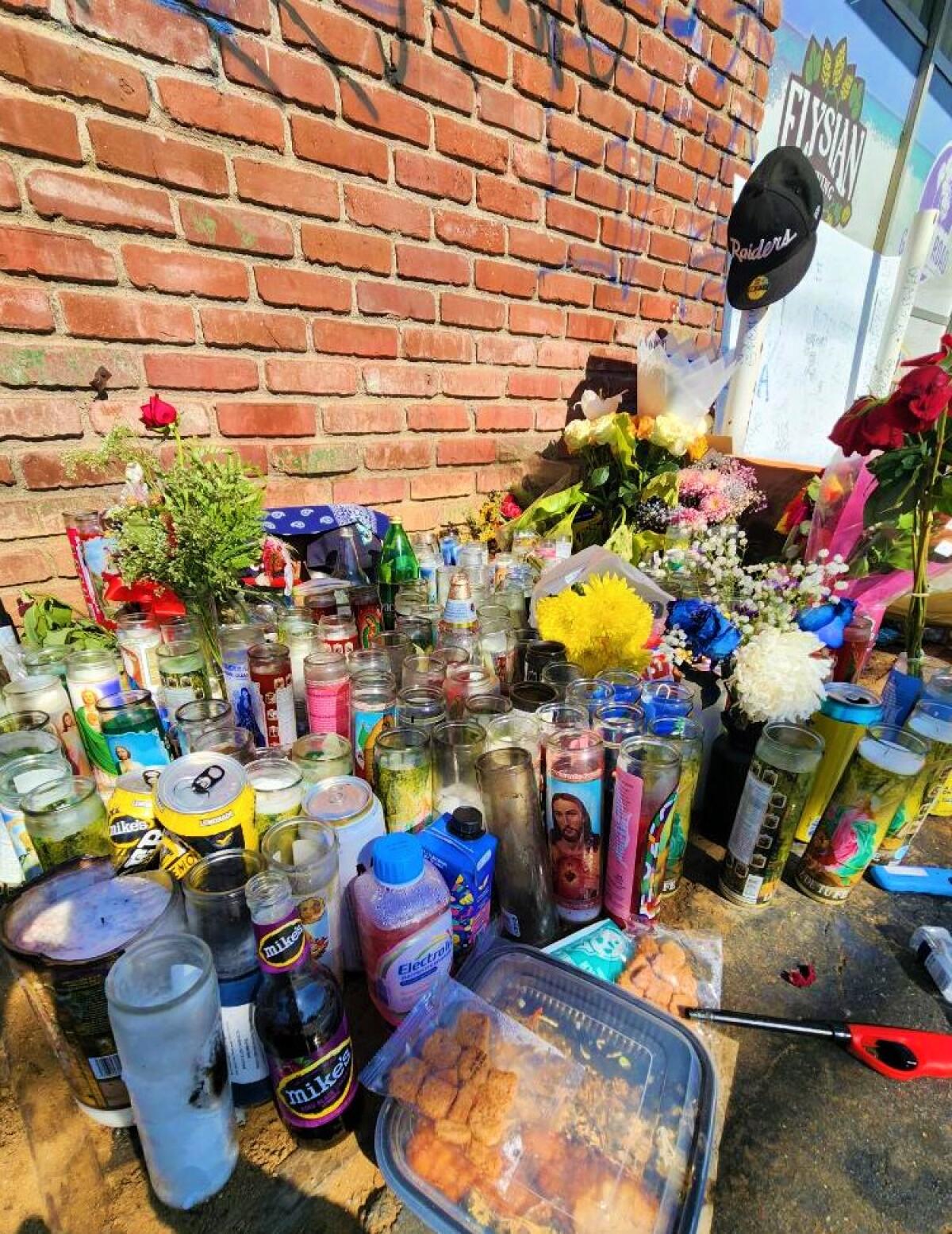Food, flowers and tributes line a wall on the 1700 block of Placentia Avenue.