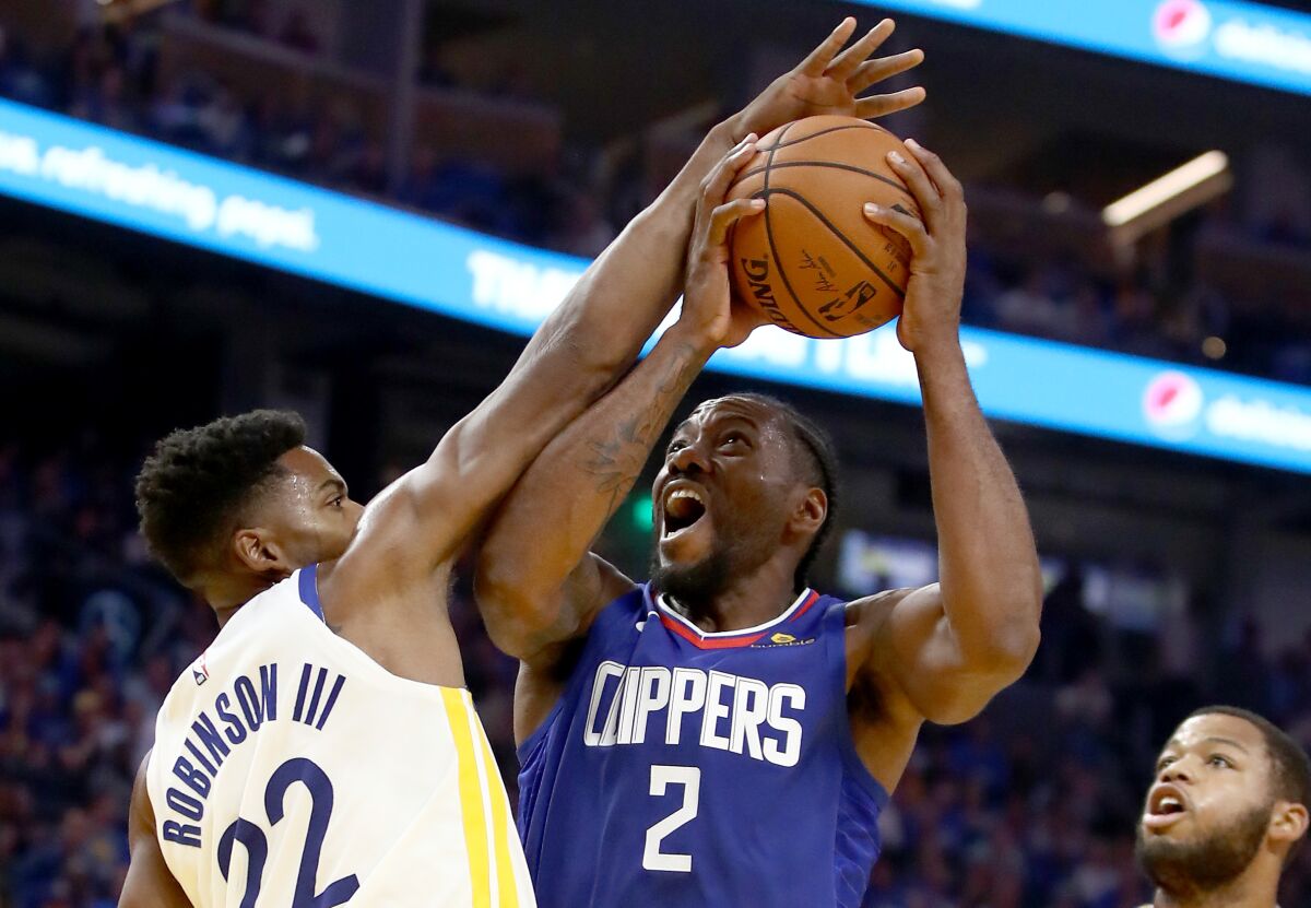 Clippers star Kawhi Leonard, right, puts up a shot over Golden State forward Glenn Robinson III.