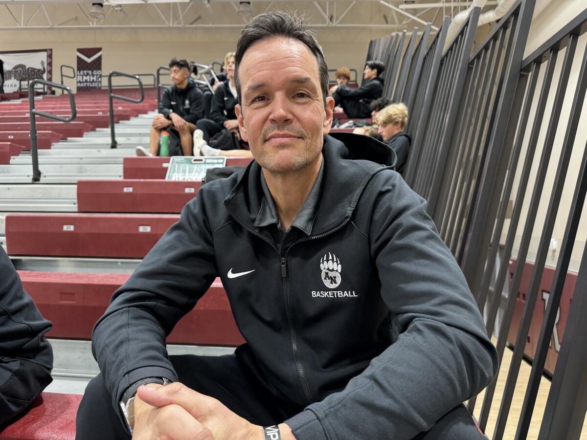 Aliso Niguel basketball coach Keith Barnett poses for a photo while sitting in bleachers.