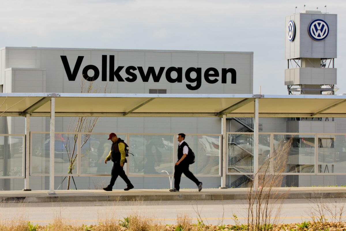 Workers walk by the Volkswagen plant in Chattanooga, Tenn.