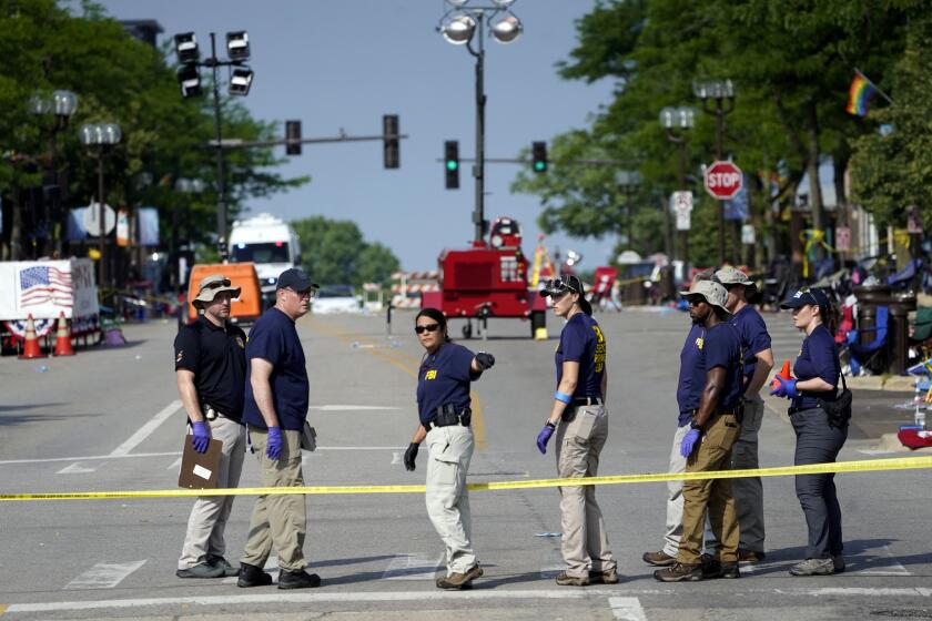 Members of the FBI's evidence response team organize one day after a mass shooting in downtown Highland Park, Ill. Tuesday, July 5, 2022. A shooter fired on an Independence Day parade from a rooftop spraying the crowd with gunshots initially mistaken for fireworks before hundreds of panicked revelers of all ages fled in terror. (AP Photo/Charles Rex Arbogast)