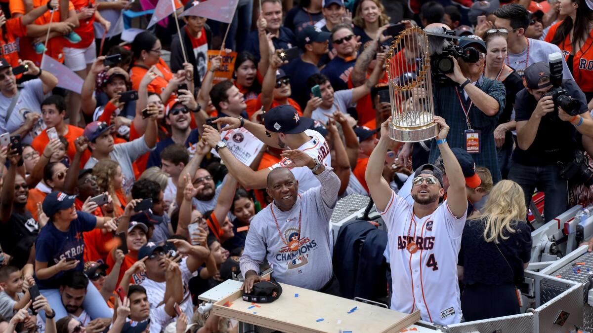 Astros right fielder George Springer holds up the World Series trophy as Houston Mayor Sylvester Turner waves to cheering crowds during a parade Friday in Houston.