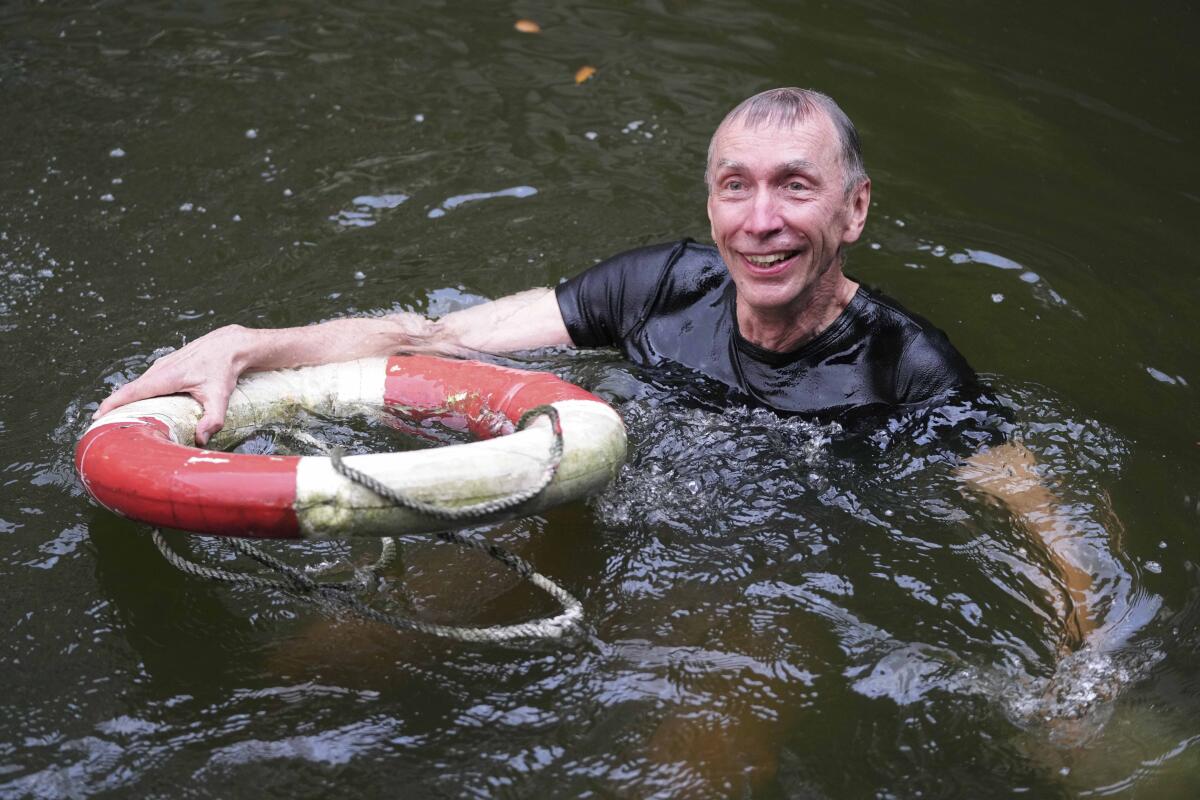 Svante Paabo holds a life preserver and smiles from a pool.