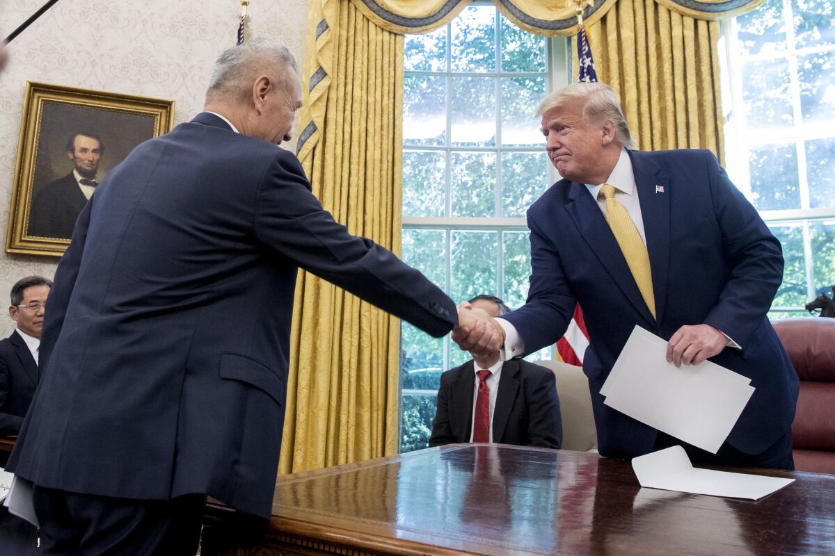 FILE - In this Oct. 11, 2019, file photo, U.S. President Donald Trump, right, shakes hands with Chinese Vice Premier Liu He after being given a letter in the Oval Office of the White House in Washington. China's trade with the United States fell by double digits again in September amid a tariff war that threatens to tip the global economy into recession. (AP Photo/Andrew Harnik, File)