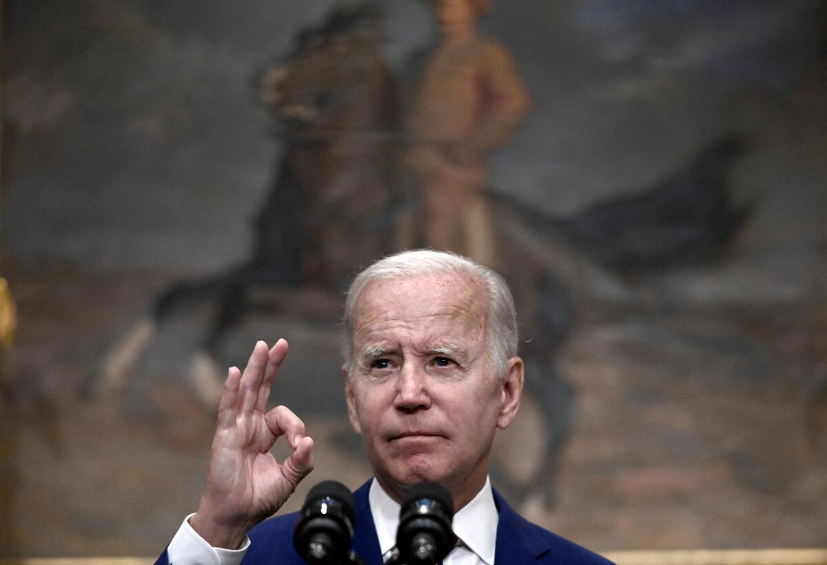 President Biden gestures while speaking at microphones