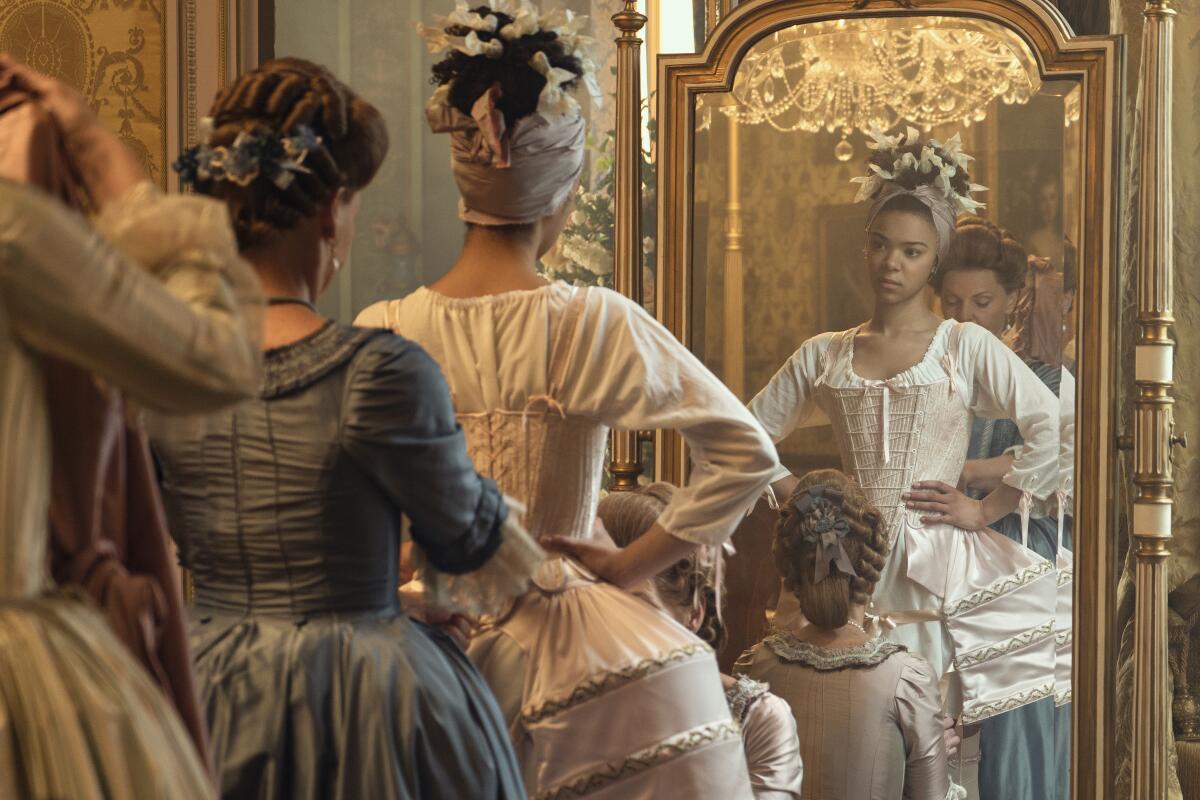 Queen Charlotte's undergarments are adjusted in a scene from"Queen Charlotte: A Bridgerton Story."