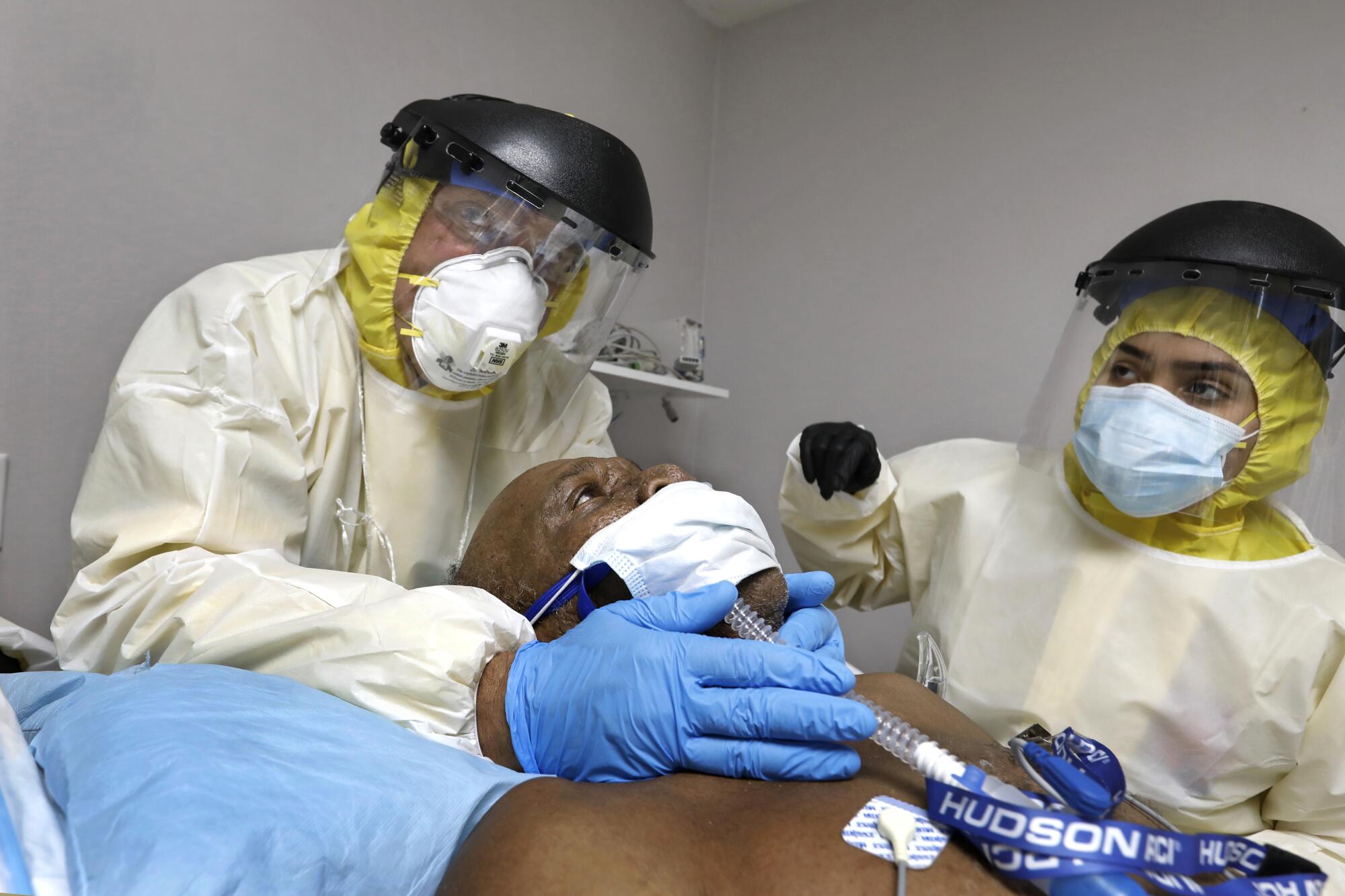 Dr. Joseph Varon, left, prepares to put a patient, Terry Hill, age 65, on a ventilator assisted by Estrella Gutierrez.