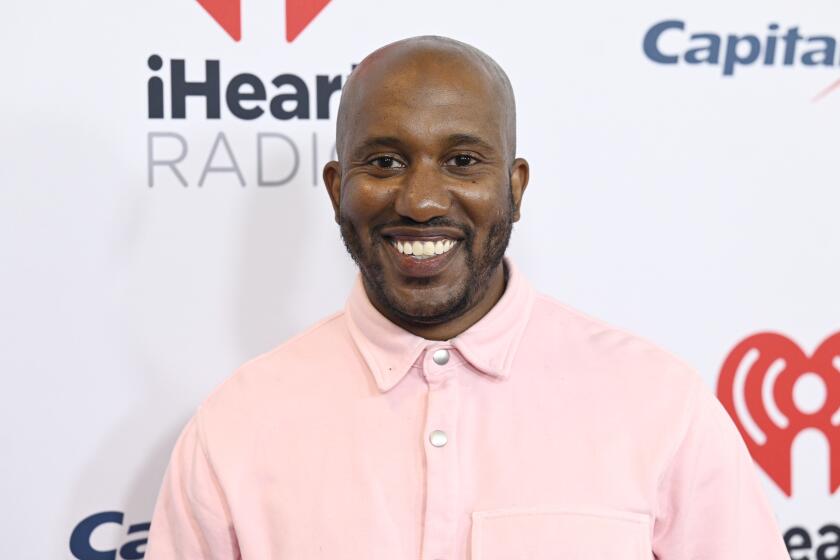 A bald man smiling in a pink button-up shirt