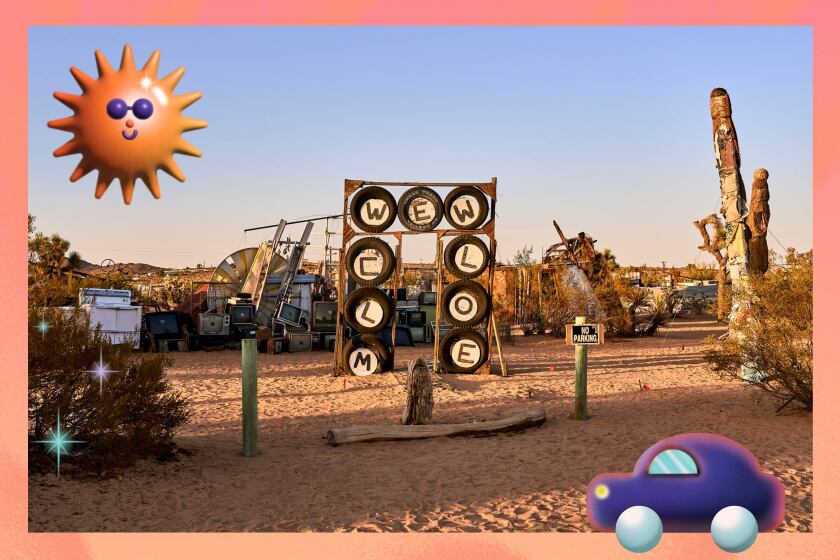 An artwork in the desert with letters that spell "welcome" and illustrations of a car and a smiling sun.