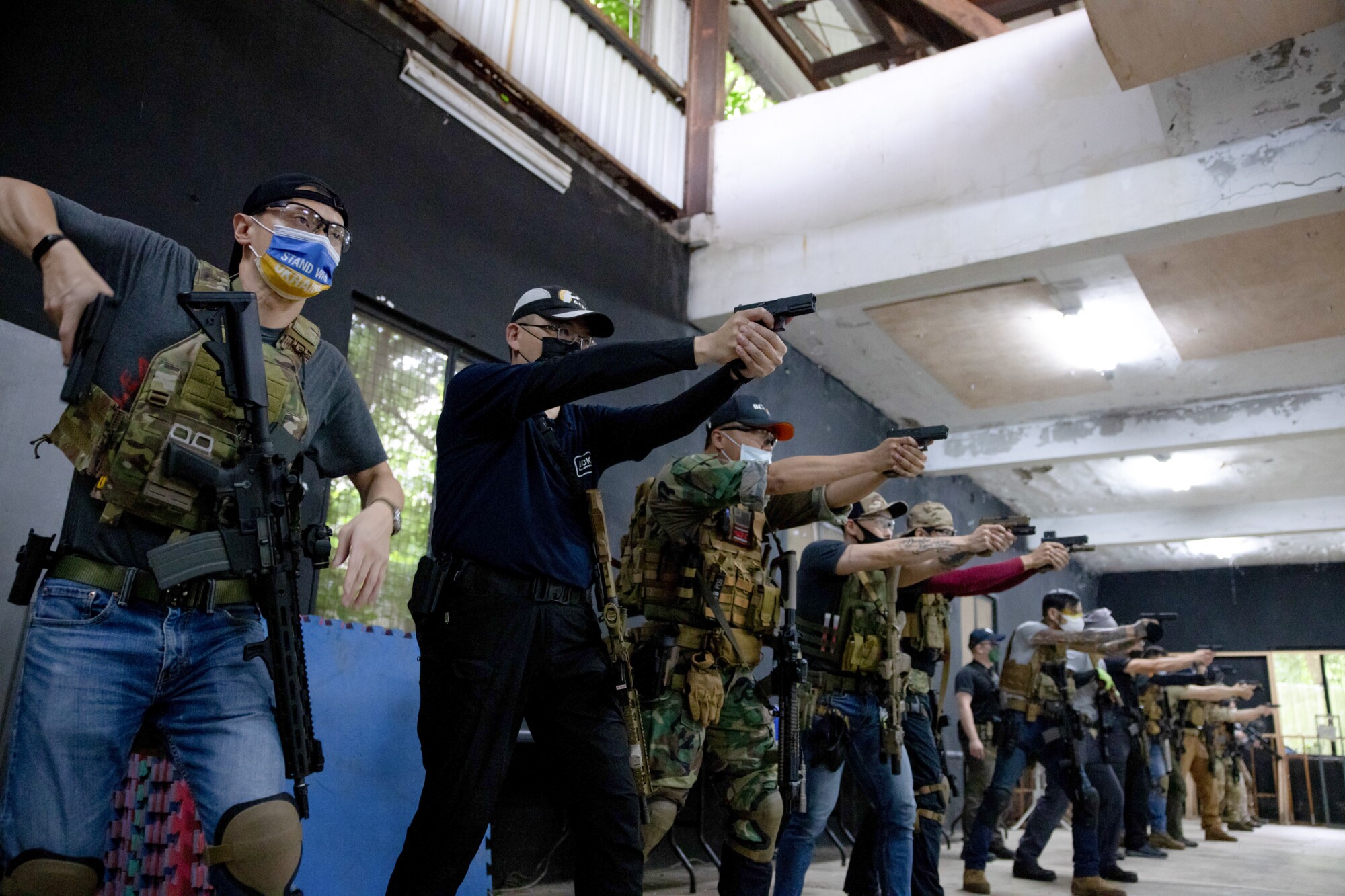 A line of people, with most of them holding and aiming handguns.