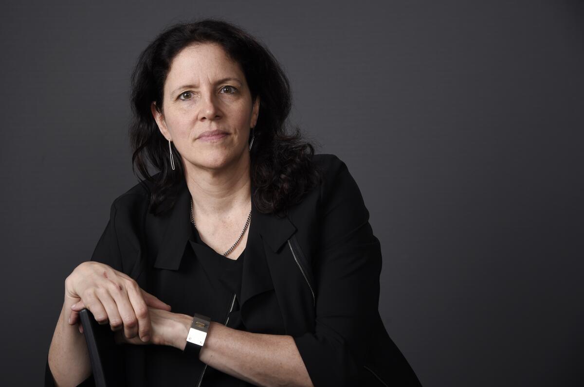 Documentary filmmaker Laura Poitras clasps her hands as she sits for portrait.