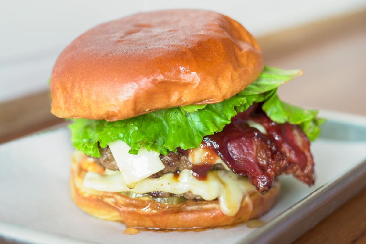 A hamburger with lettuce, halal bacon and cheese.