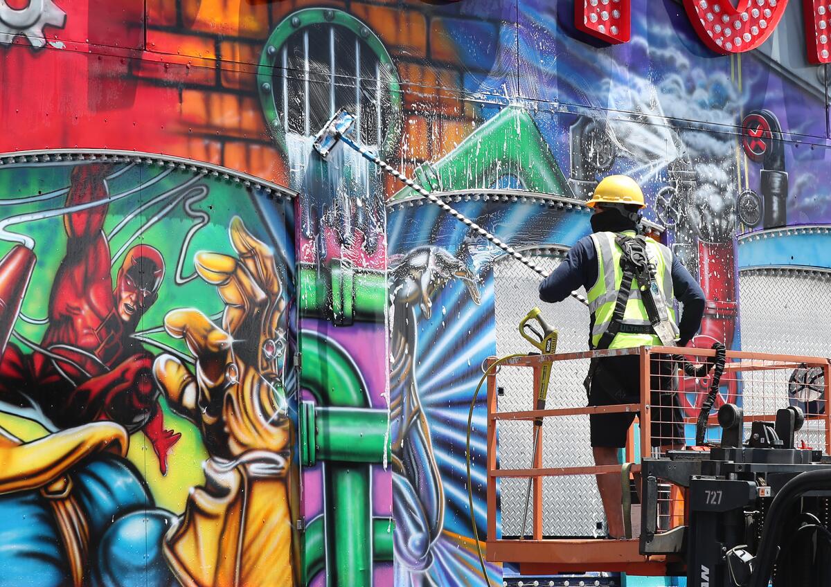 A worker scrubs the facade of the Fun Factory ride during preparations for the OC Fair on Friday afternoon.