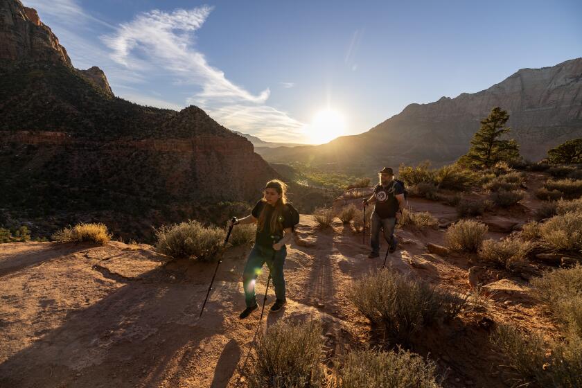 Zion National Park, UT - November 03: Soleil Mandel, 12, left, and her dad Duncan Mandel, right, head back to camp after a late afternoon hike on the Watchman Trail during the Atheist Adventure 2023 on Friday, Nov. 3, 2023 in Zion National Park, UT. (Brian van der Brug / Los Angeles Times)