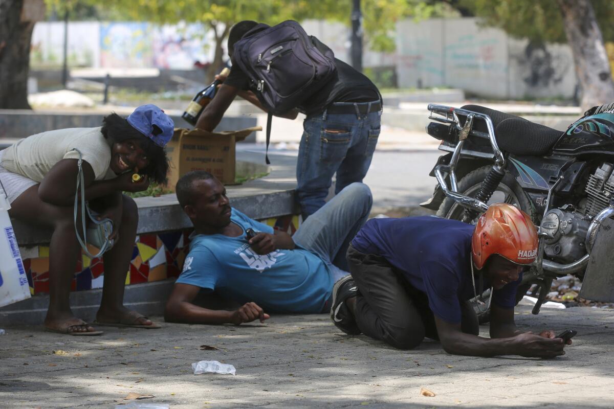 People take cover from gunfire during clashes between police and gangs in Port-au-Prince, Haiti.