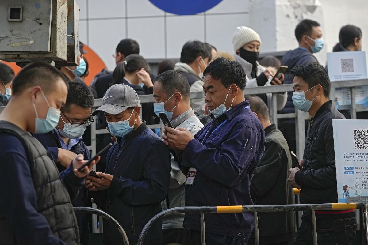 Service sector workers wearing face masks to help curb the spread of the coronavirus line up during a mass COVID-19 testing in Beijing on Oct. 29, 2021. As vaccination rates rise in many parts of of the world and even countries that previously had strict COVID-containment strategies gingerly ease restrictions, China is doubling down on its zero-tolerance policy. (AP Photo/Andy Wong)