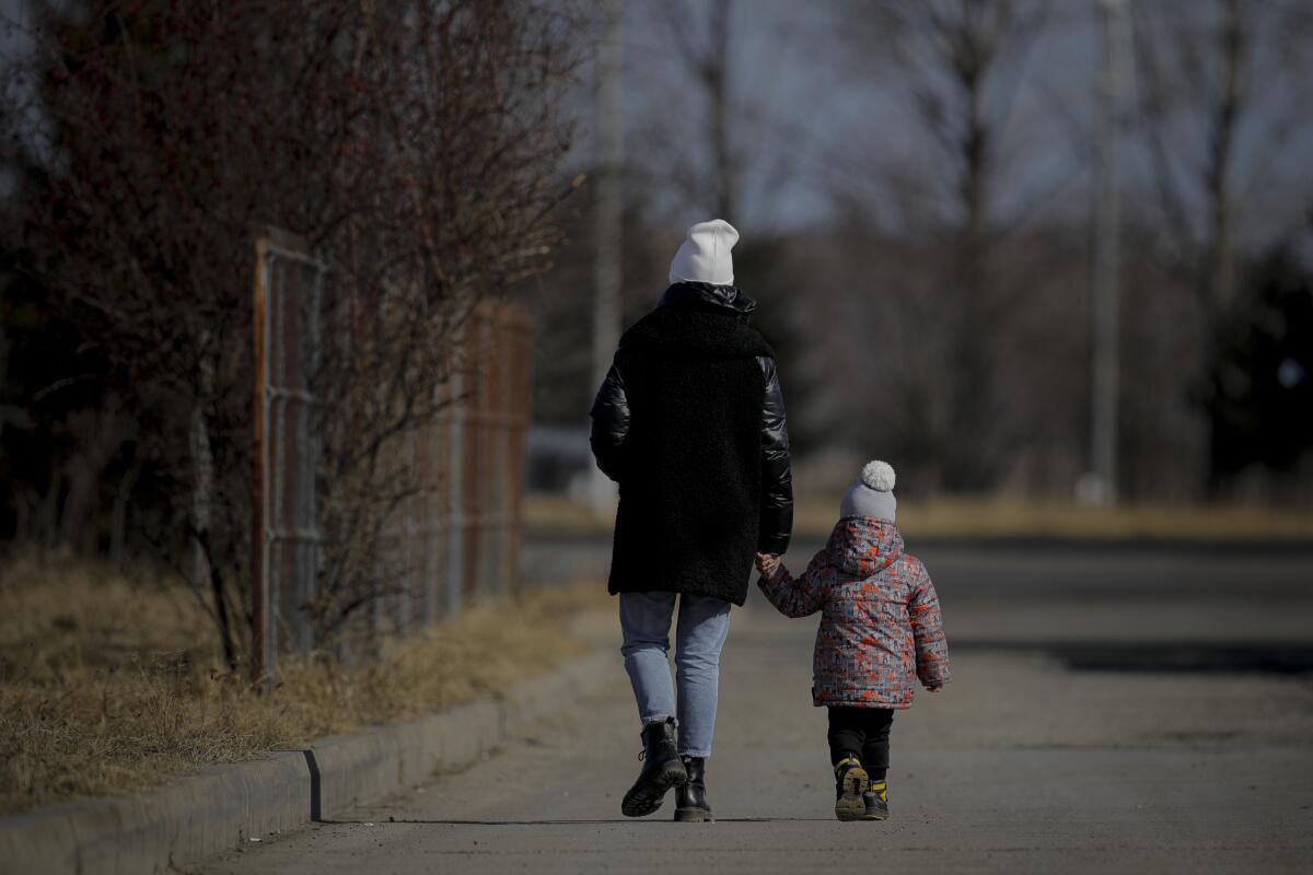 A woman holds a child's hand after crossing the border from Ukraine into Romania.